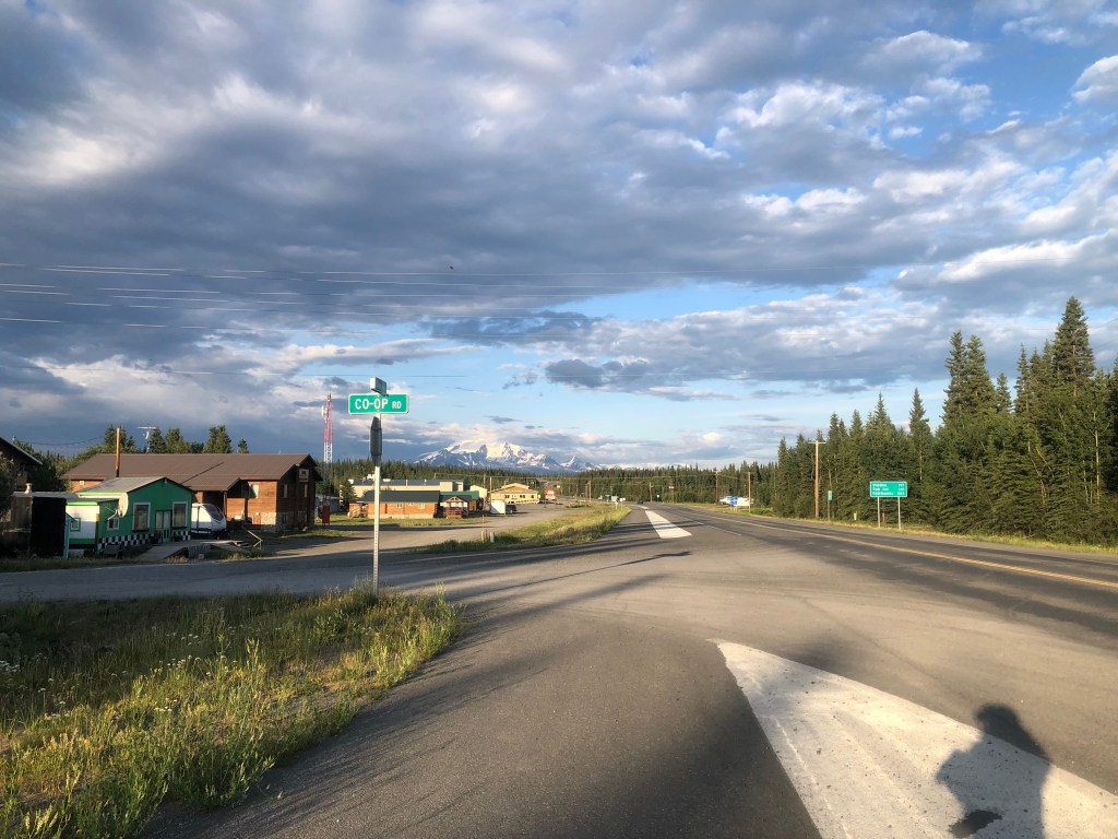 View of a small-town skyline with a majestic Alaskan mountain shrouded by clouds in the background