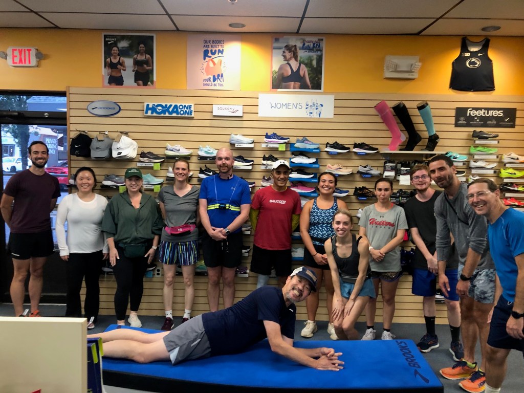 Runners standing in front of running-shoe display with CtCloser stretched out on store bench in front