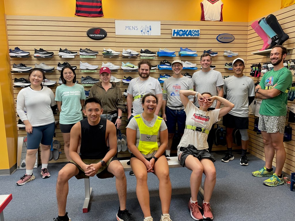 Runners standing and sitting on bench in front of men's running shoes