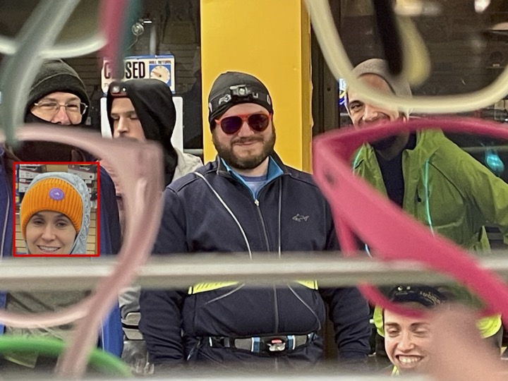 Runners as seen through a sunglass display with one centered and visually unobstructed who's wearing an orange-framed pair from the display. Another is cut and pasted in with a bright red border.