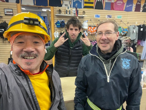 A selfie with 2 runners flanking a mugging staff member behind the counter