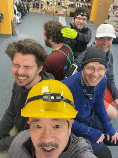 A selfie with guys seated back to back on a store bench. One completely turned from the camera.