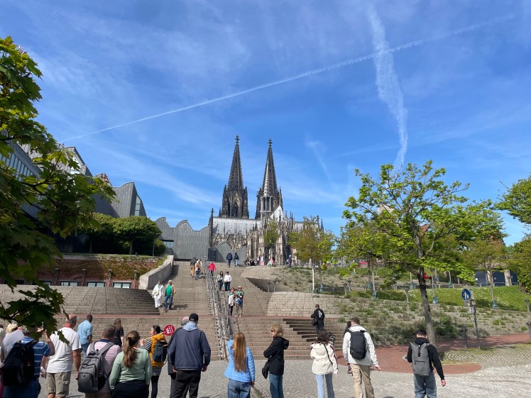 Looking up from the promenade to see double steeples behind nearer building at the top of 3 sets of broad steps.