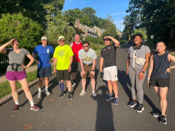 Runners across the street at the bottom of hill brilliantly lit by a bright sun